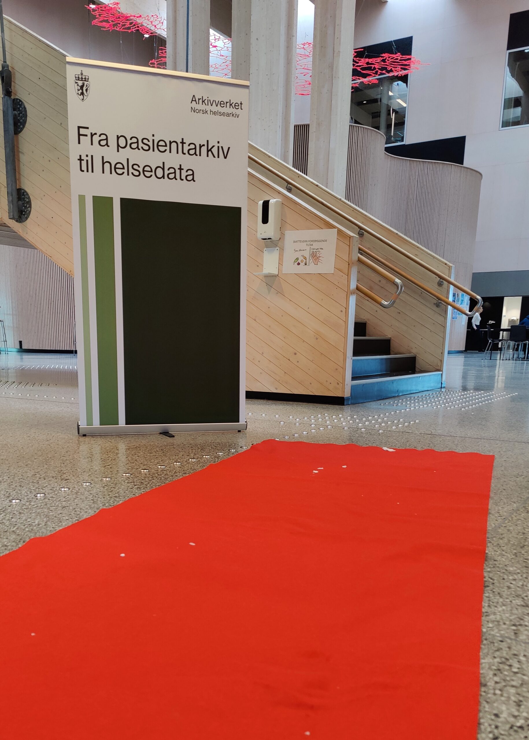 Rød løper mot trappa i Tunet på Nord-Østerdal videregående skole. Roll-up hvor det står: Fra pasientarkiv til helsedata.